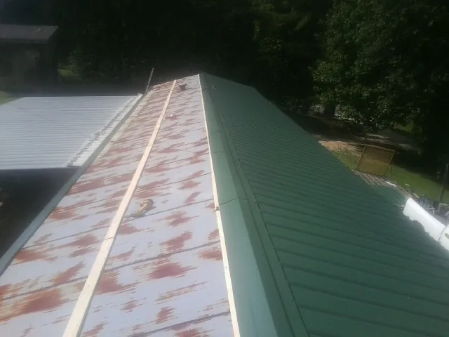 Old rusted panels beside newly installed green metal roofing — Wind Damage Roof Repair by Roofing Brothers in Underwood