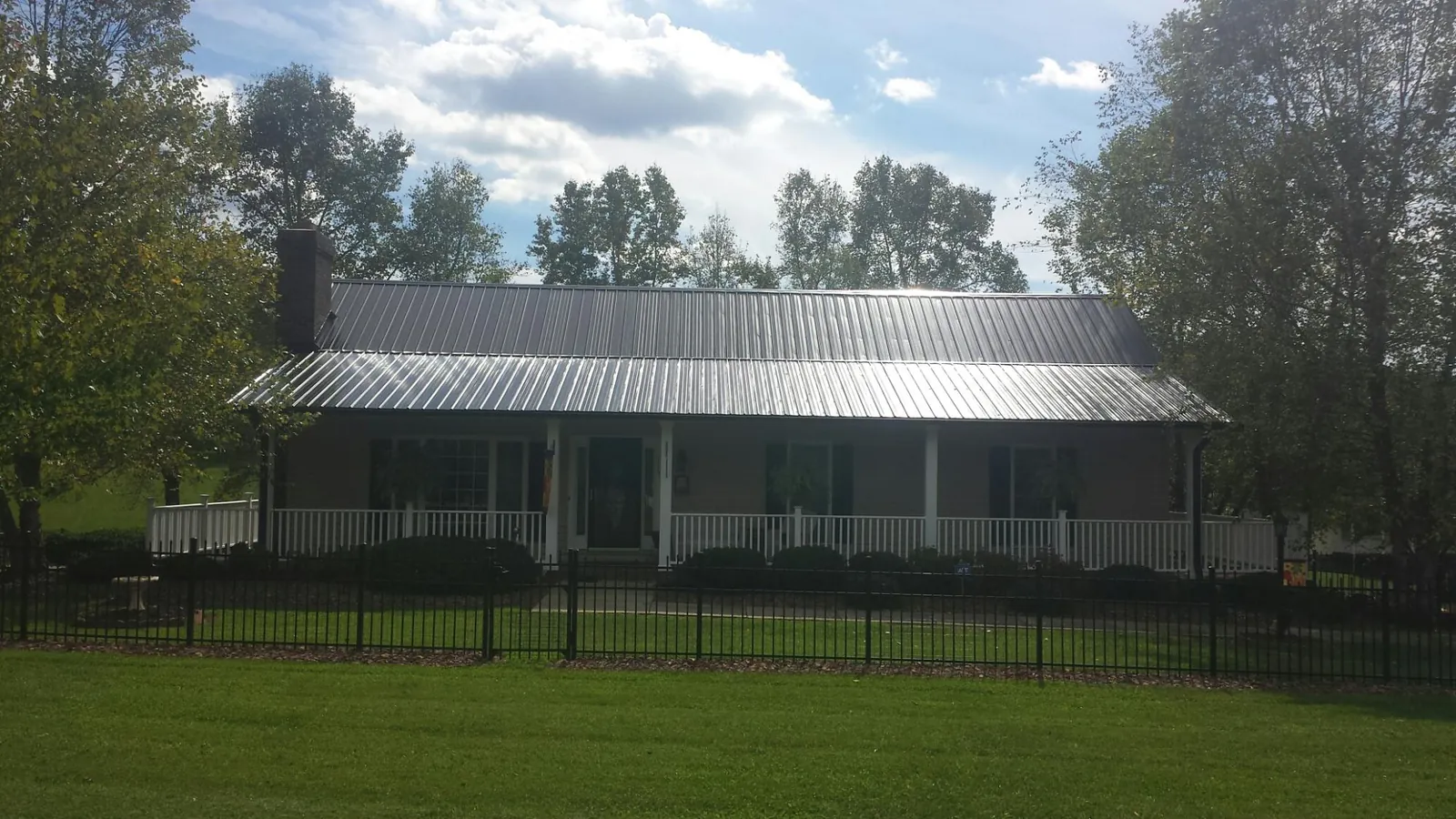 Gray metal roof on a brick ranch with a full width front porch — Gutter Guard Installation work by our crew in Underwood
